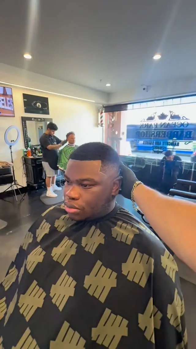 Barber finishing a sharp lineup inside Ocean Park Barbershop