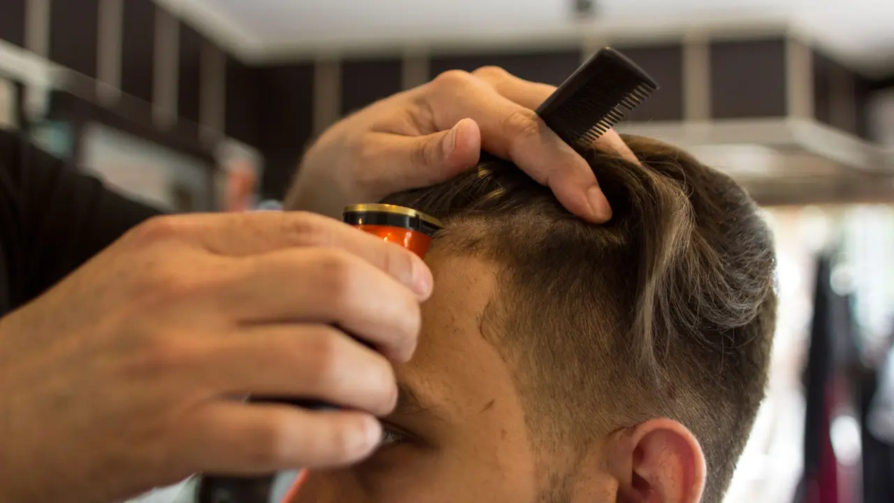 Barber carefully trimming the hairline of a young client