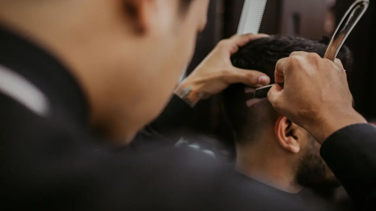 Barber detailing a specialty cut with a straight razor