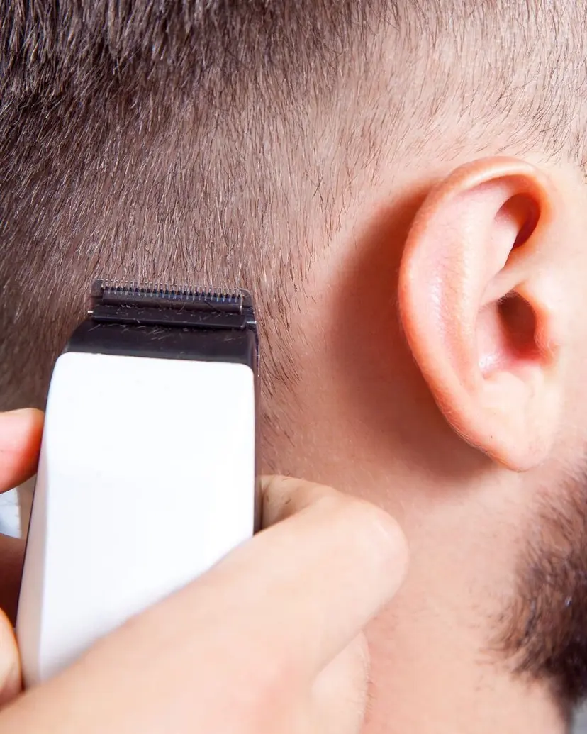 Trimmer cleaning the edge of a fade behind the ear