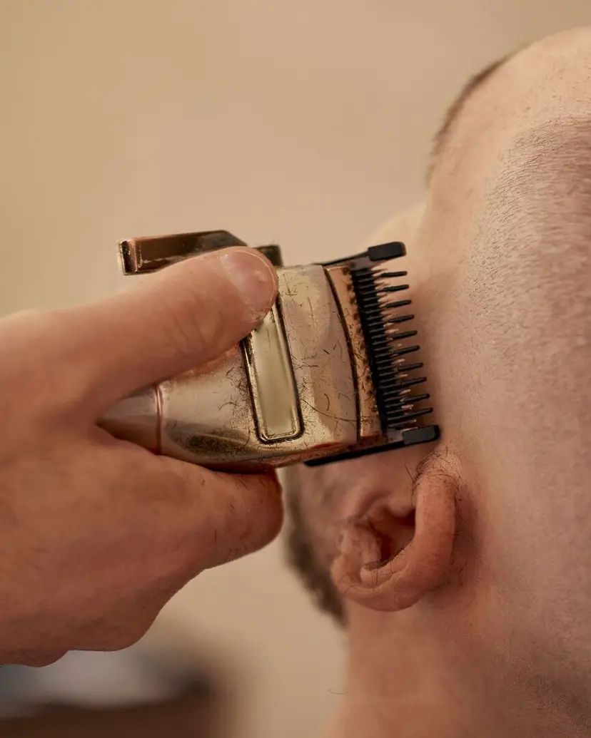 Clippers with a guard trimming short hair at the temple