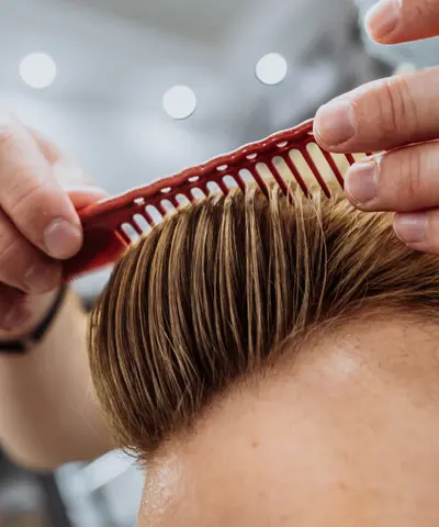 Comb lifting the top of a finished comb over haircut