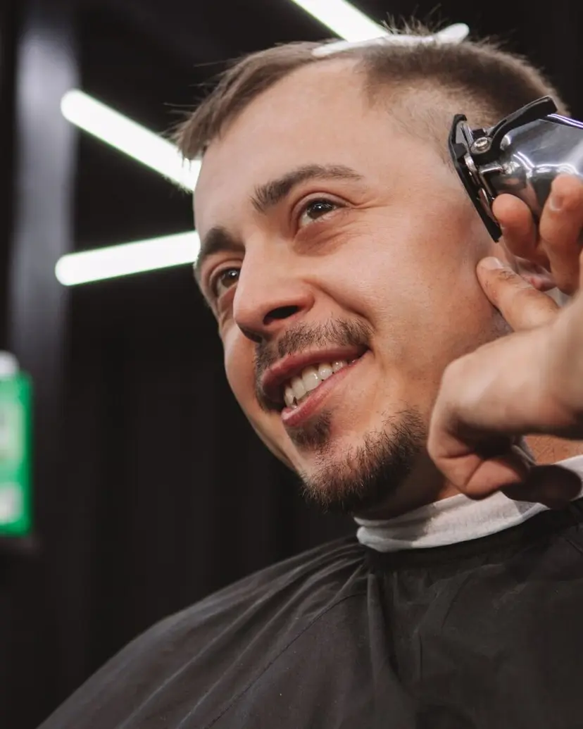 Smiling client in a barber chair getting a clipper cut