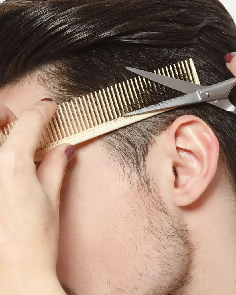 Scissors and comb trimming hair above the ear