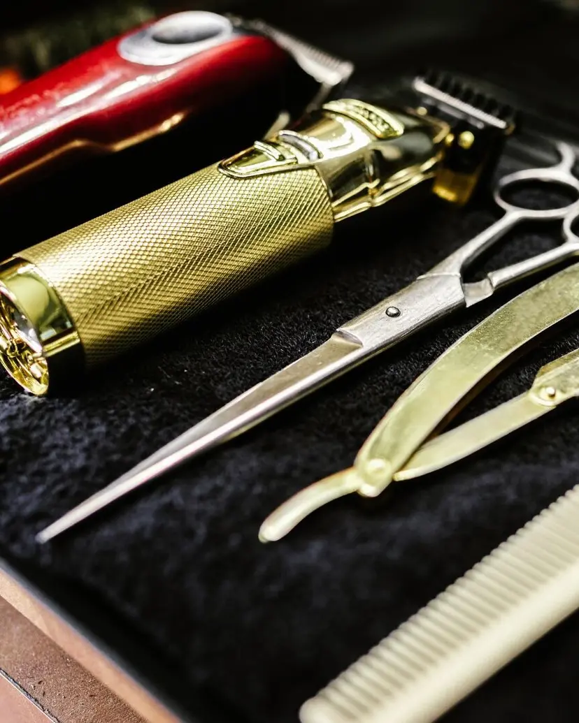 Clippers, shears, razor, and comb laid out on a barber station