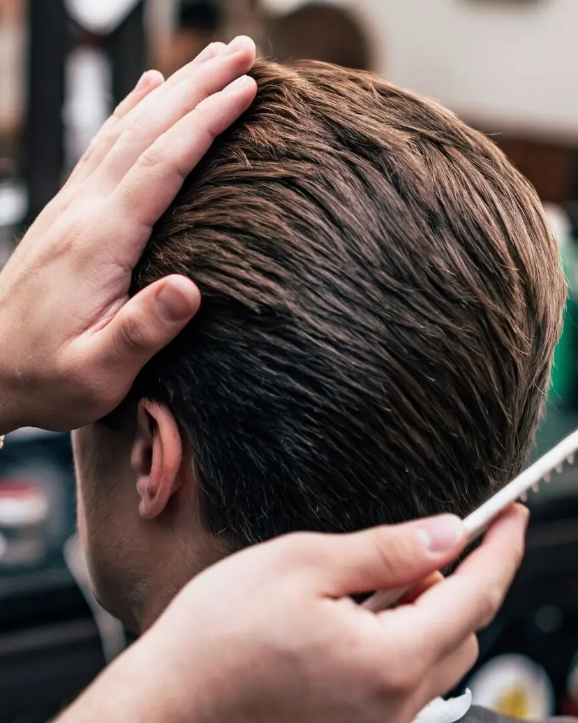 Barber combing and smoothing a finished haircut by hand