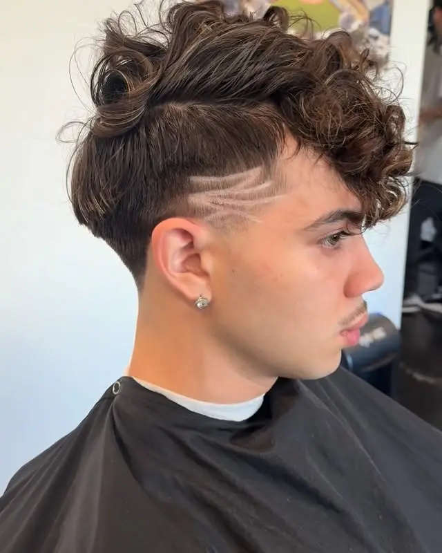Curly top haircut with a taper and razor design lines