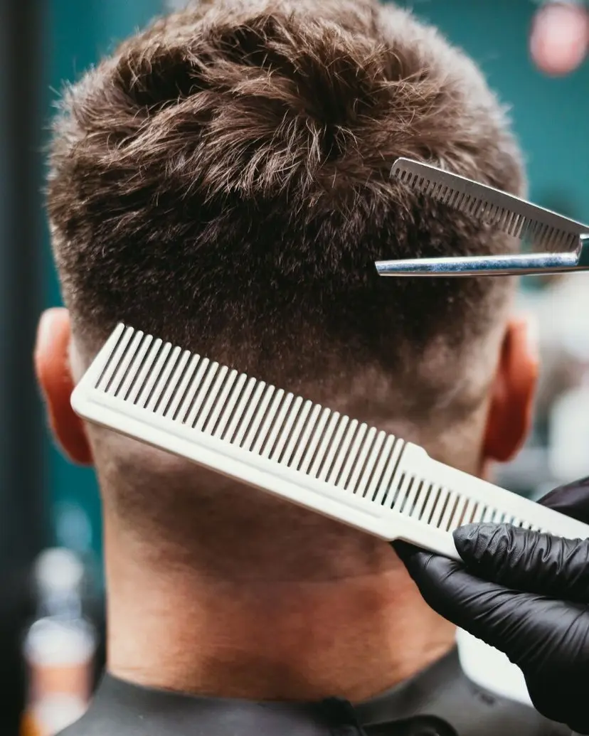 Barber using thinning shears and a comb on the back of a client's head