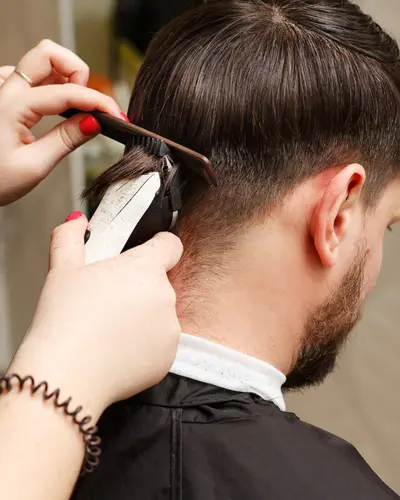 Barber trimming the back of a client's haircut with clippers and a comb