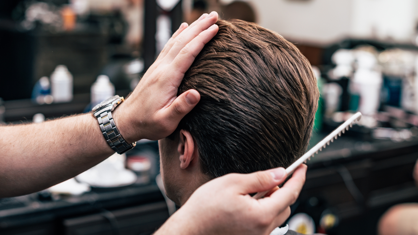 A man getting his hair cut at a barber shop